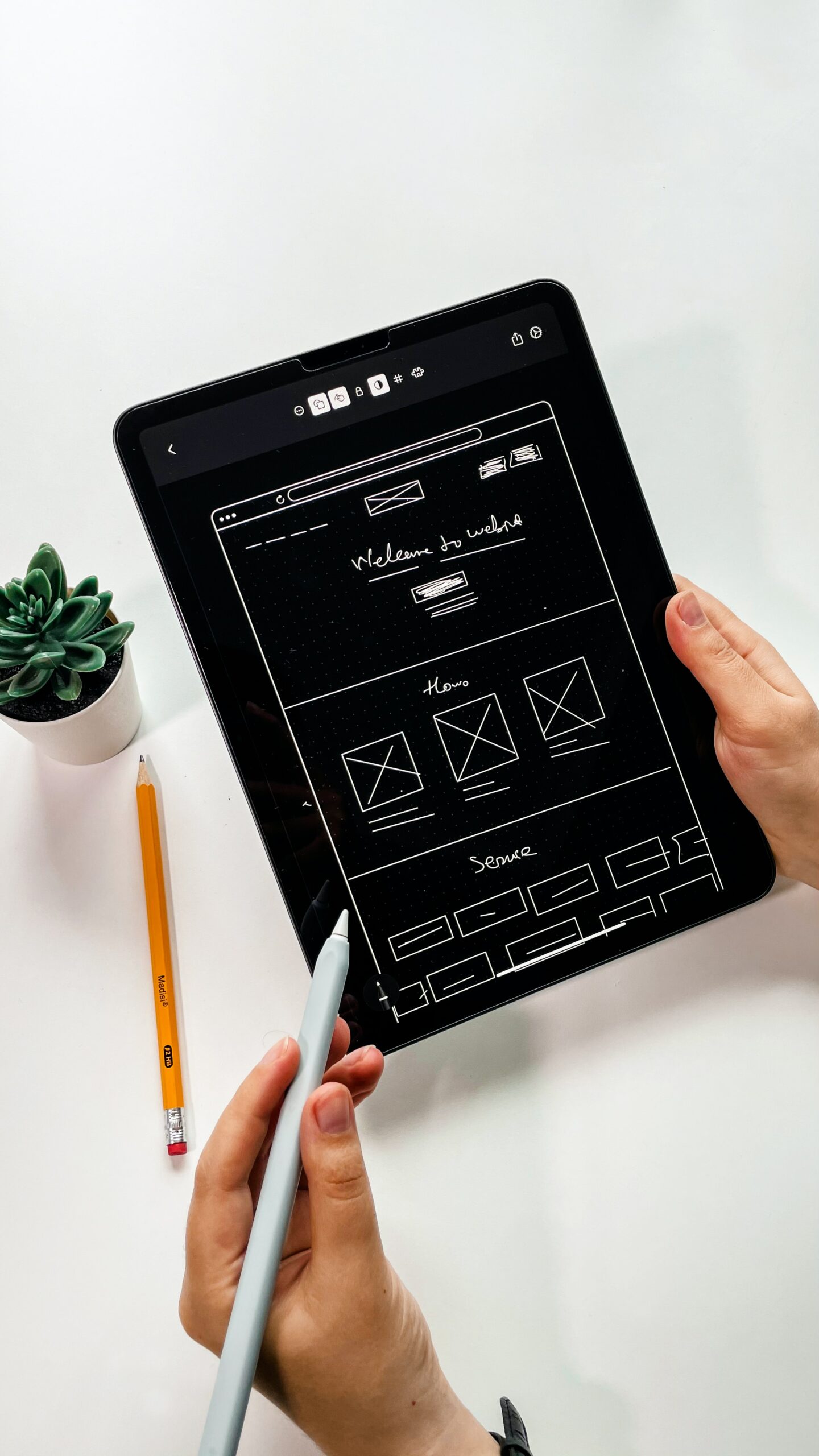 Tablet med wireframe af hjemmeside, sort skærm med hvid illustration